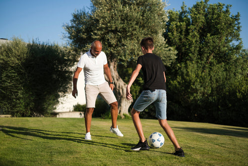 man and child playing soccer