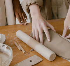 hands rolling out ceramic clay on a table