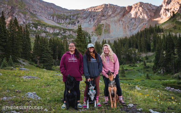 3 dog owners pose with their pets in the mountains of Colorado wearing Natural Rapport shirts
