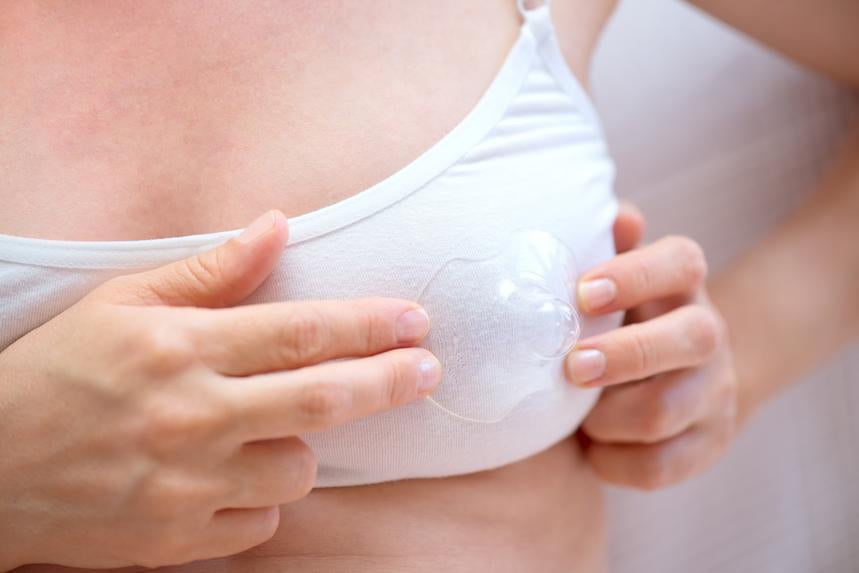 woman placing a nipple shield over one of her breasts (bra on) showing how to use it