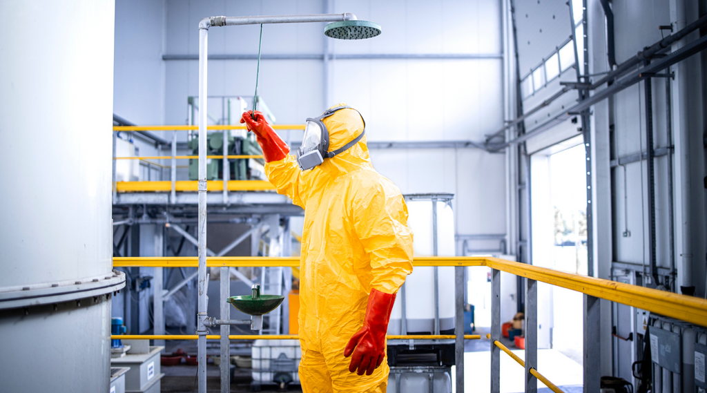 trabajador en ppe usando ducha de seguridad