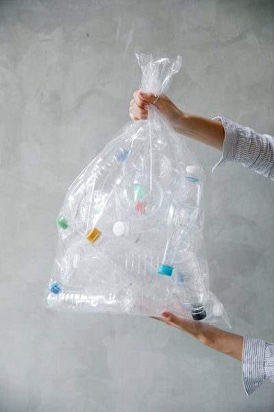 hands holding a plastic bag filled with plastic bottles