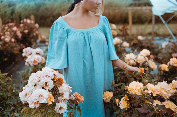woman in blue dress walking among flowers