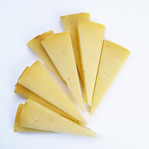 sliced wedge of face rock clothbound cheddar on white background