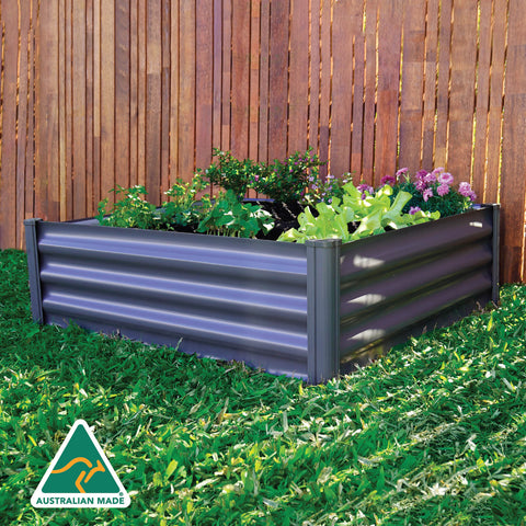 The Absco 4' x 4' Metal Garden Bed AB1305 with plants in a backyard, featuring an Australian Made icon.