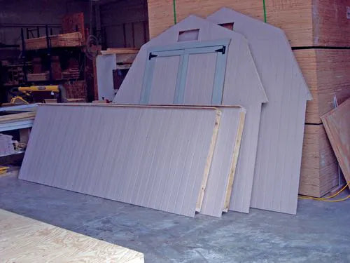 a man assembling the pre-cut walls of a Little Cottage Co storage shed