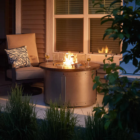 The Fire Pit Table in operation during the evening, with visible flames and nearby outdoor furniture.