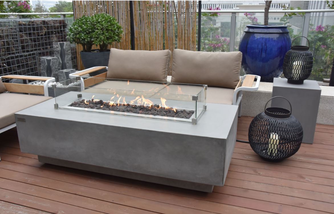 Elementi Granville Fire Table with the lit fire surrounded by the wind guard on an outdoor setting