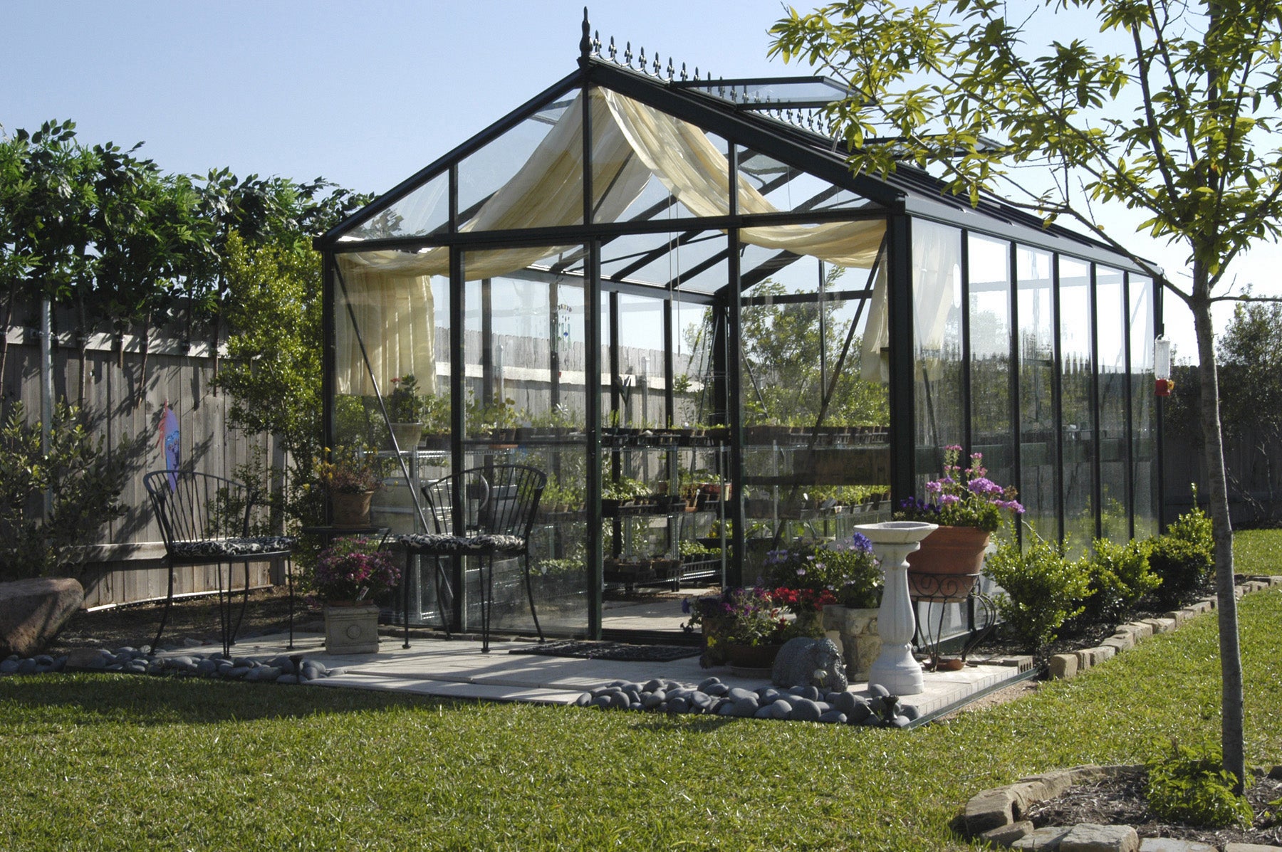 Elegant design of an Exaco Janssens Victorian VI-34 greenhouse with spacious interior and garden tools visible through the glass.