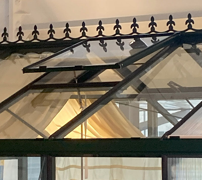 Exaco Royal Victorian greenhouse roof vents open for ventilation, with sunlight shining through.