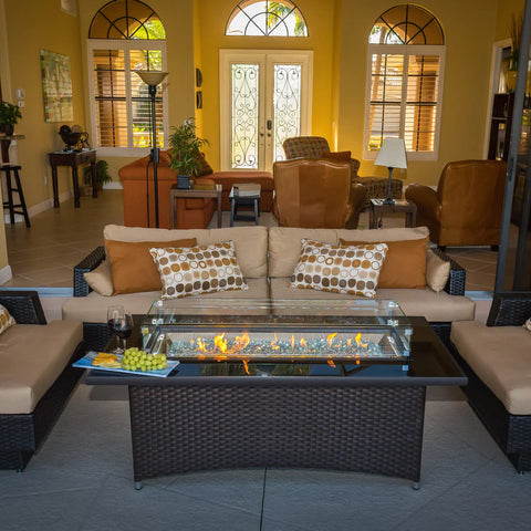 The Fire Pit Table lit with flames, with indoor seating and decorative elements around it.