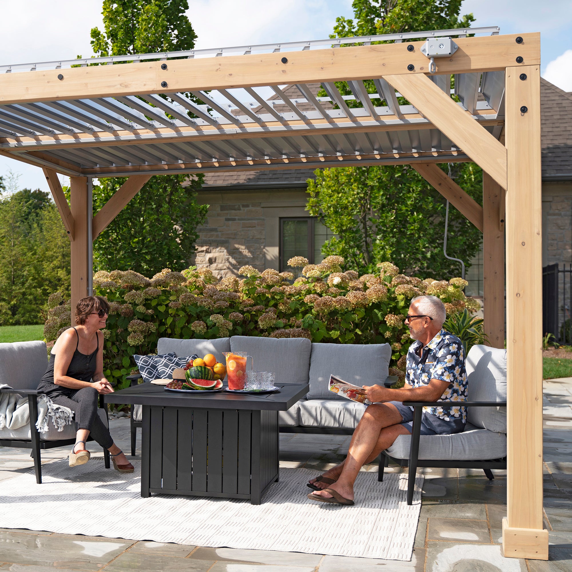 Yardistry Wood Room shown with its louvered roof and full wooden structure from an external view with a couple.