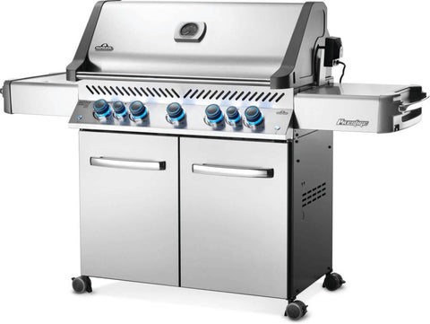 Angled view of the Napoleon Grills Prestige® 665 RSIB showcasing the stainless steel finish and blue illuminated control knobs.