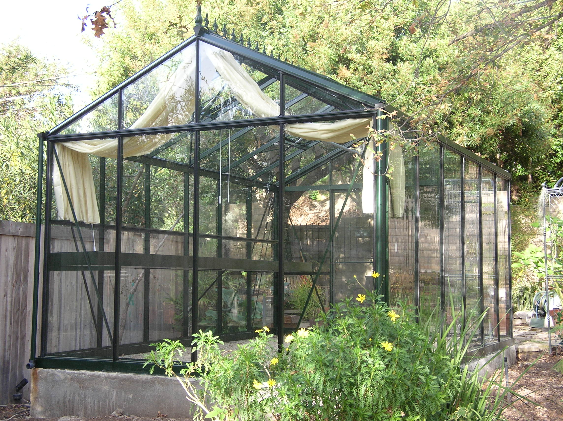 Patio view of a VI-34 Royal greenhouse by Exaco, showcasing its classic design and integration into a residential garden.