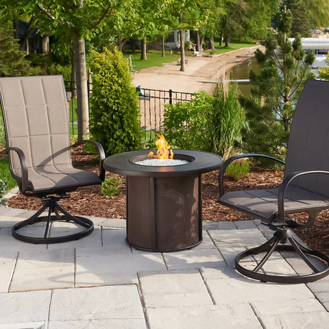 The Fire Pit Table lit with flames, with outdoor seating and decorative elements around it.