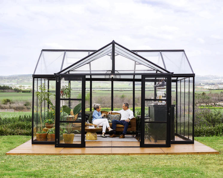 a couple sitting inside the Canopia Greenhouse Triomphe Chalet 12x15