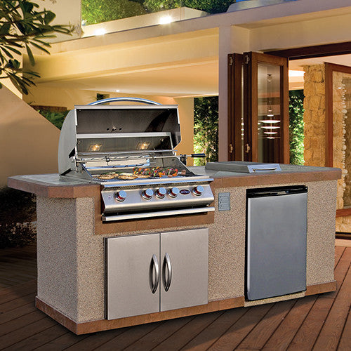 A stylish outdoor BBQ island setup featuring the Cal Flame 8 ft BBQ Island BBK-810. The island includes a large grill with multiple burners, a double-access storage cabinet, and a stainless steel refrigerator. It is set in a well-lit, modern backyard with wooden decking.
