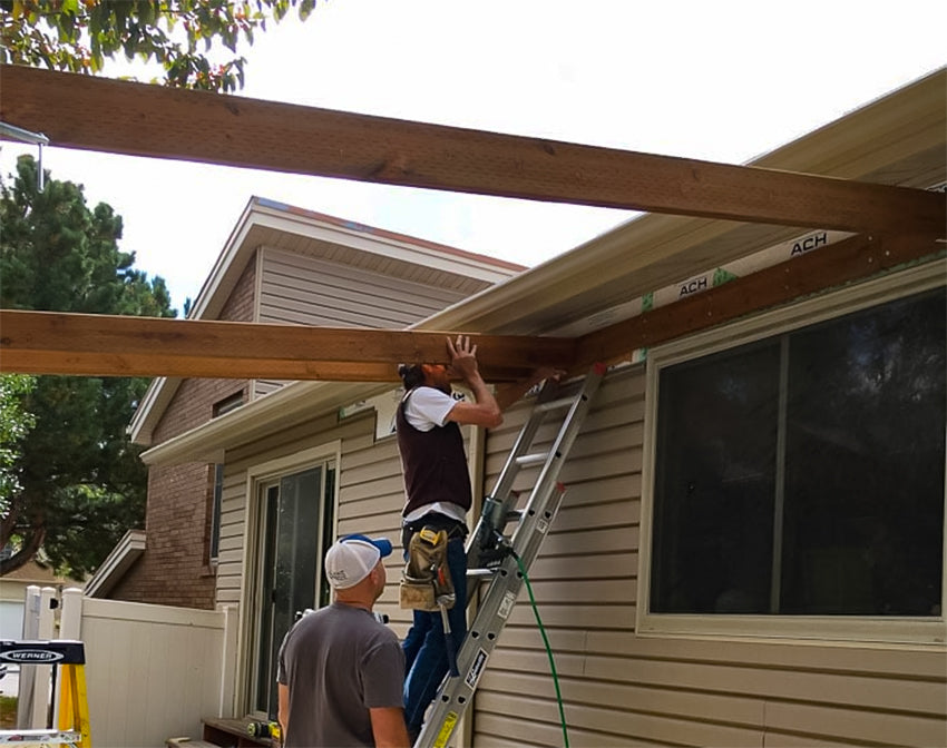 contractor working on attaching a pergola to a house