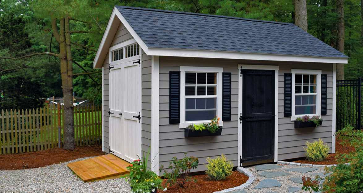 large wooden shed painted gray with double doors and transom windows