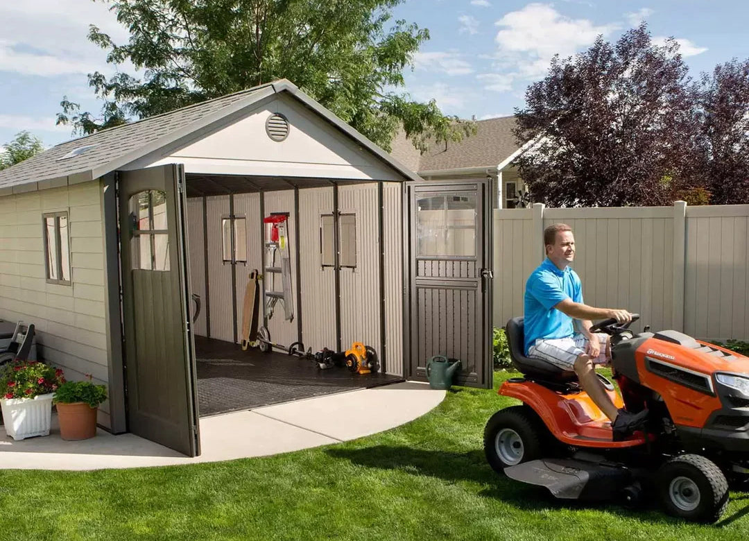 lifetime storage shed and a man riding a lawn tractor out of the shed