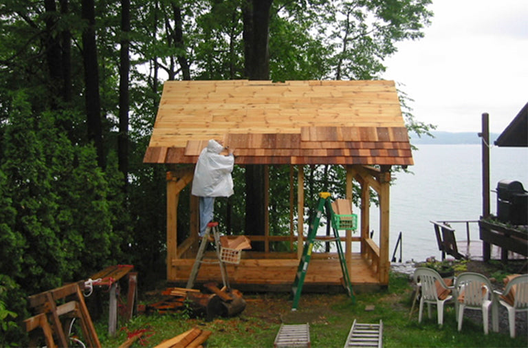 man installing wood shingles on a wooden gazebo