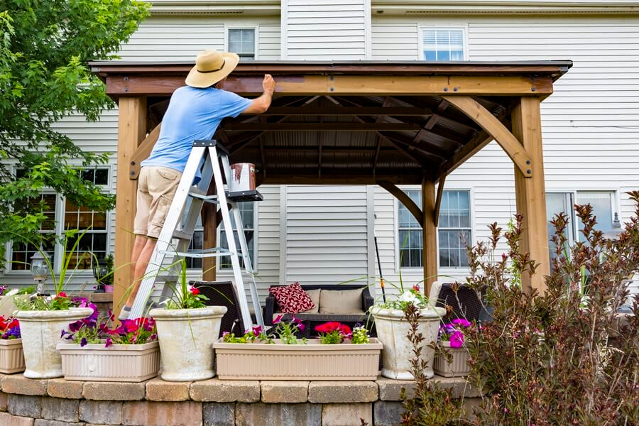 man staining a wooden gazebo