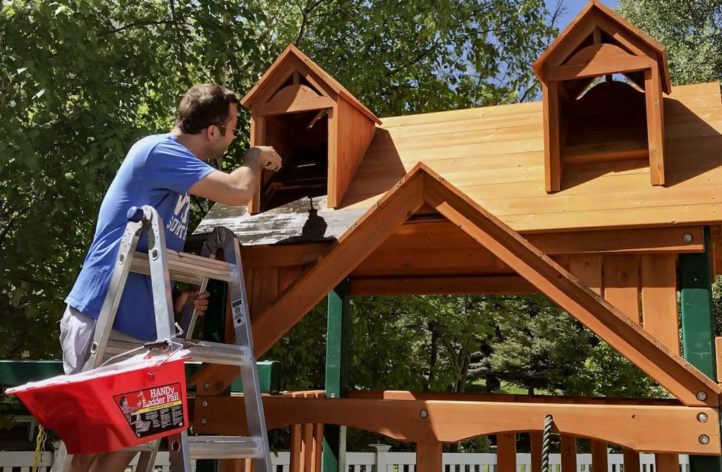 man painting a wooden playset