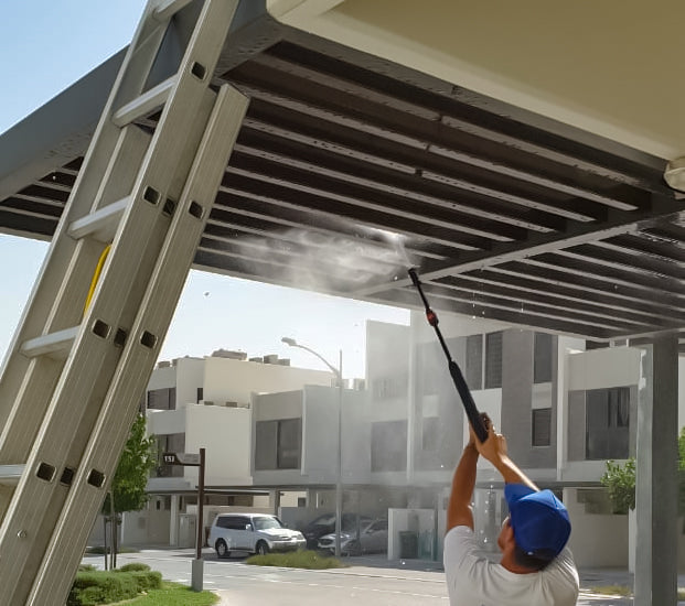 man power washing a pergola