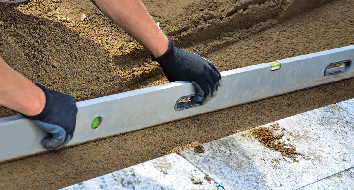 pair of hands holding a level bar measuring ground flatness