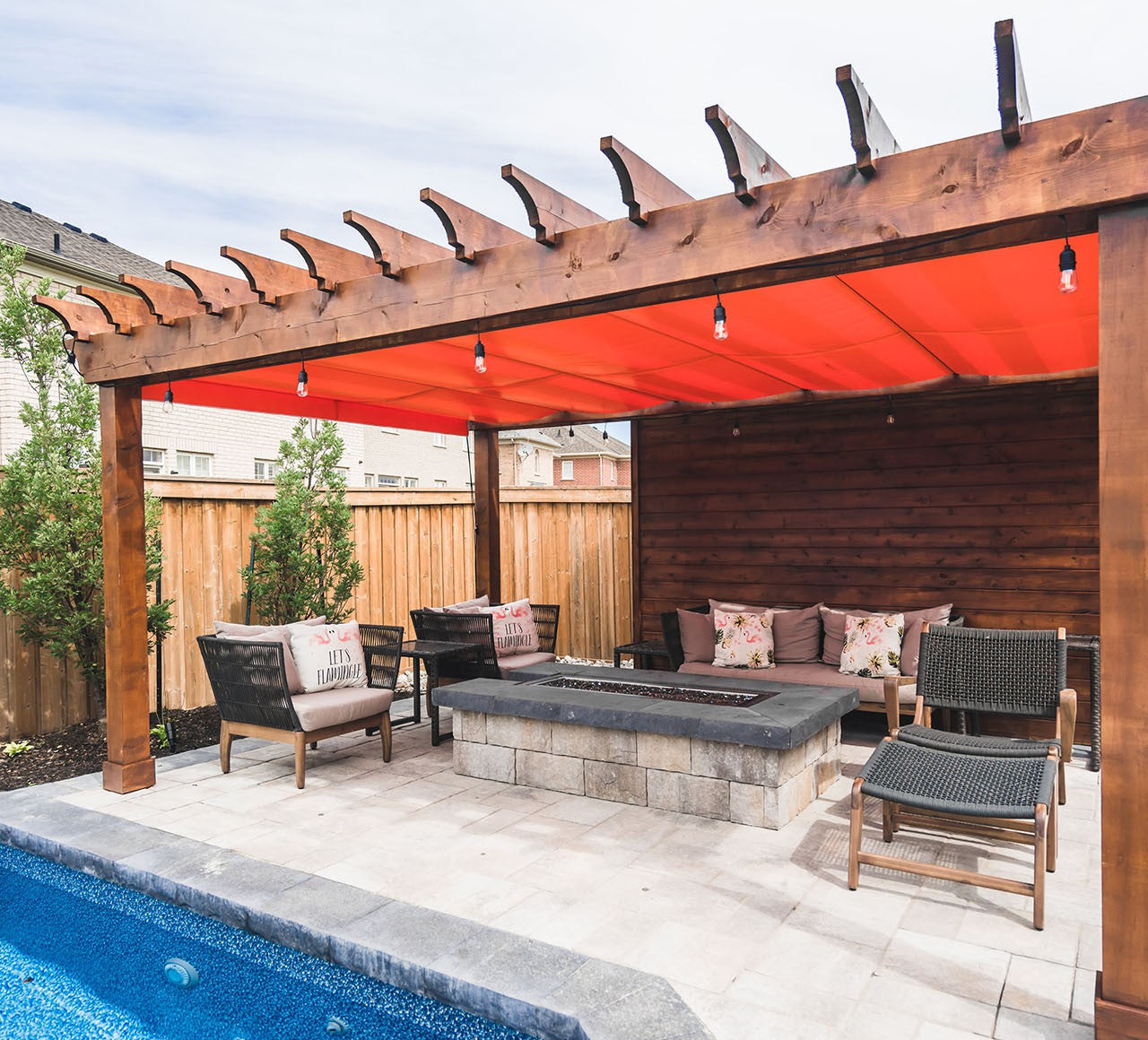 pergola with orange retractable canopy and sidewall with outdoor furniture and firetable
