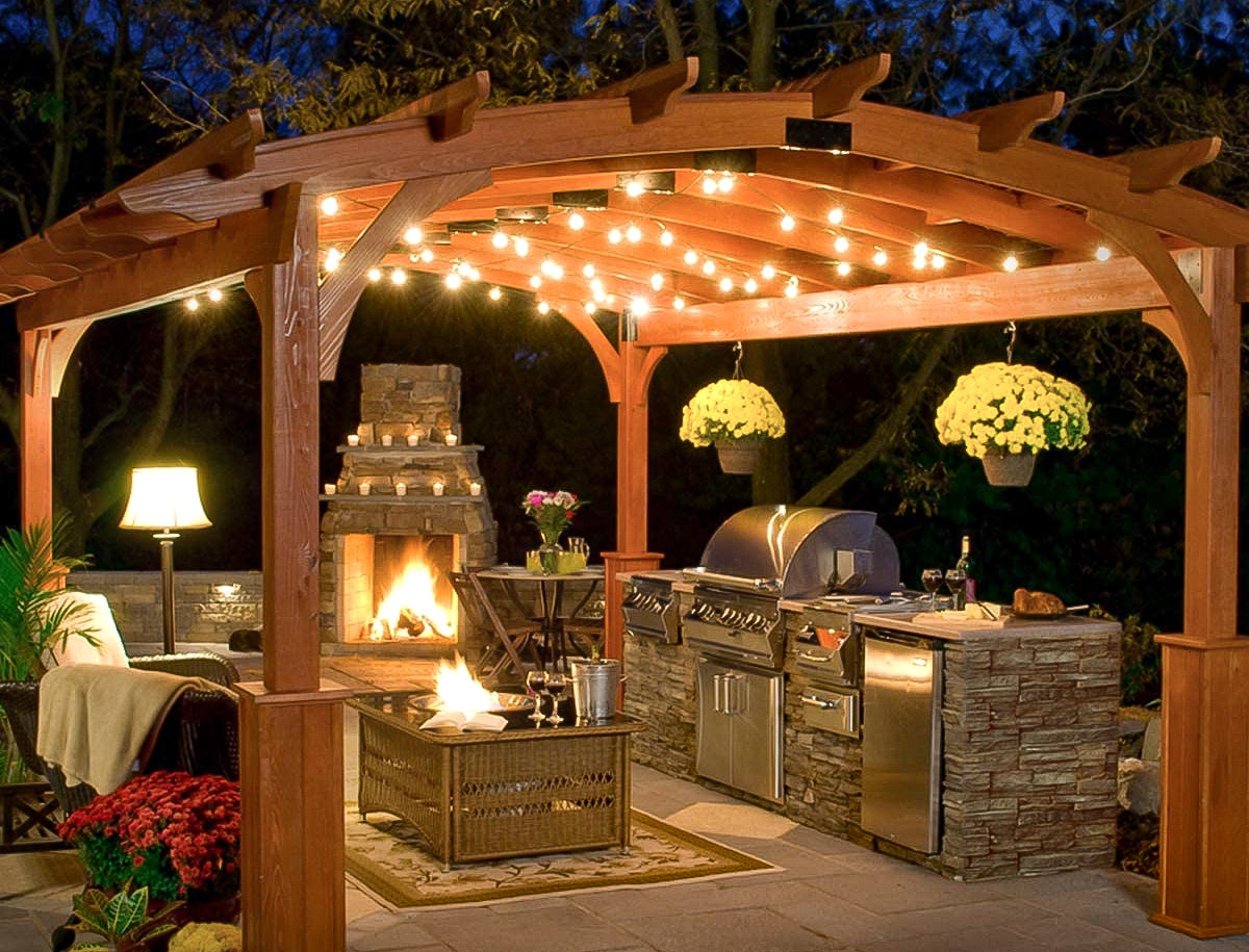 pergola with outdoor string lights with outdoor seating and grill and fireplace