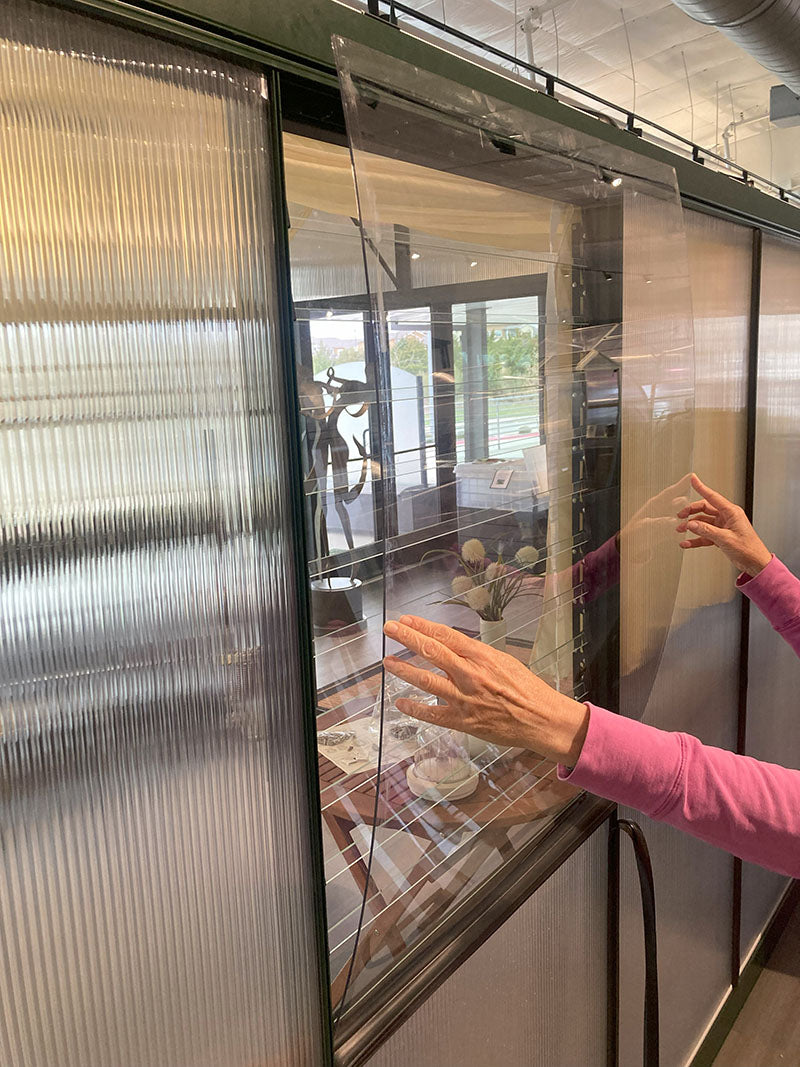 Person adjusting a partially open louvre window cover with transparent panels, showcasing indoor privacy and outdoor visibility