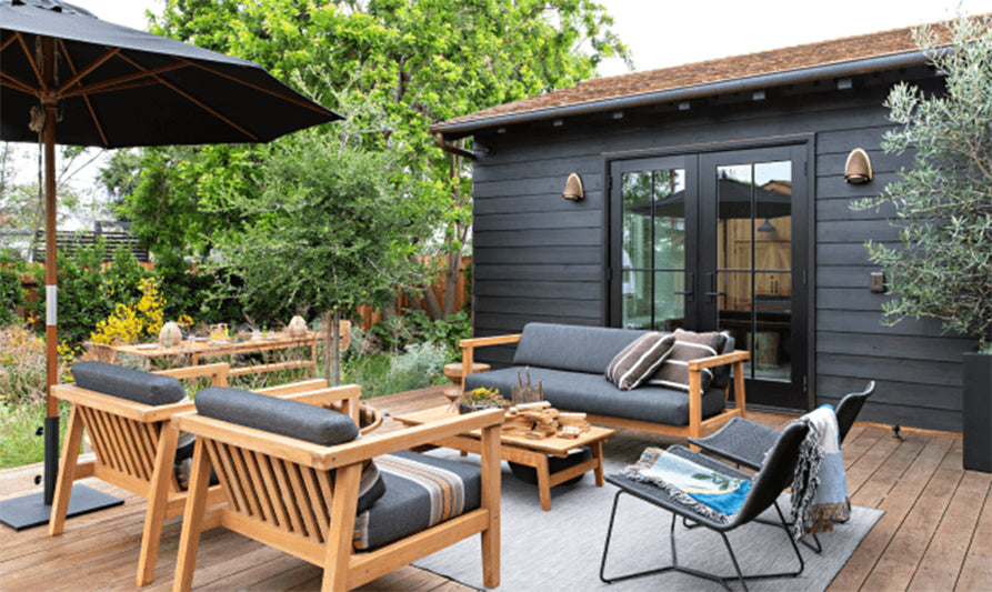 shed painted black on a deck with outdoor furniture