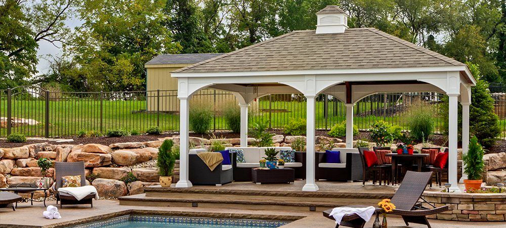 white gazebo raise on a concrete deck beside pool with outdoor furniture