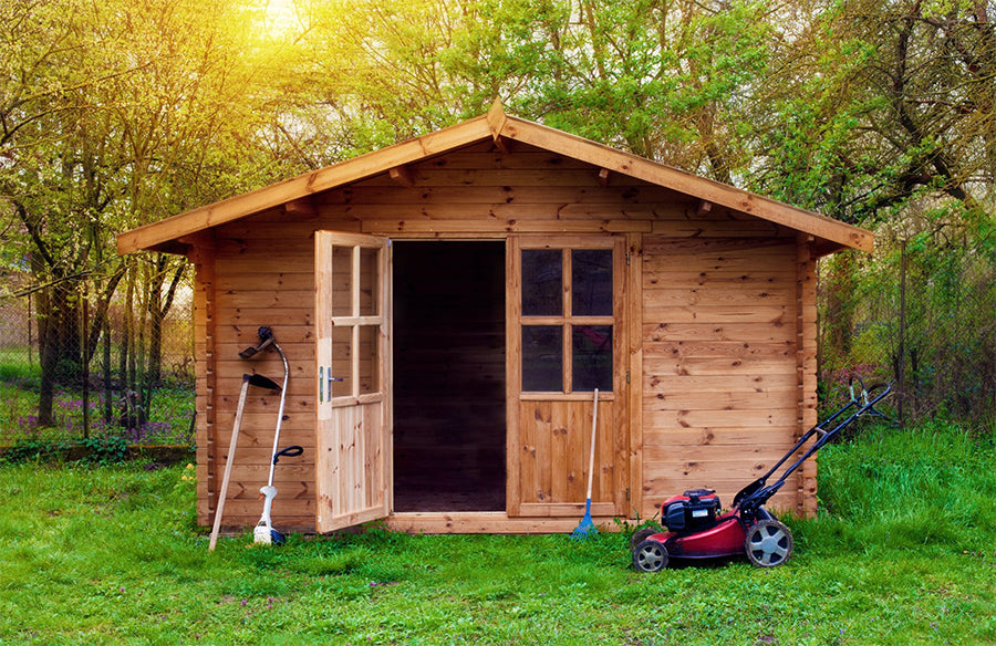 wooden shed with one door open and gardening tools around