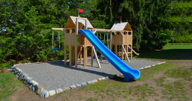 wooden playset with one slide on a pea gravel