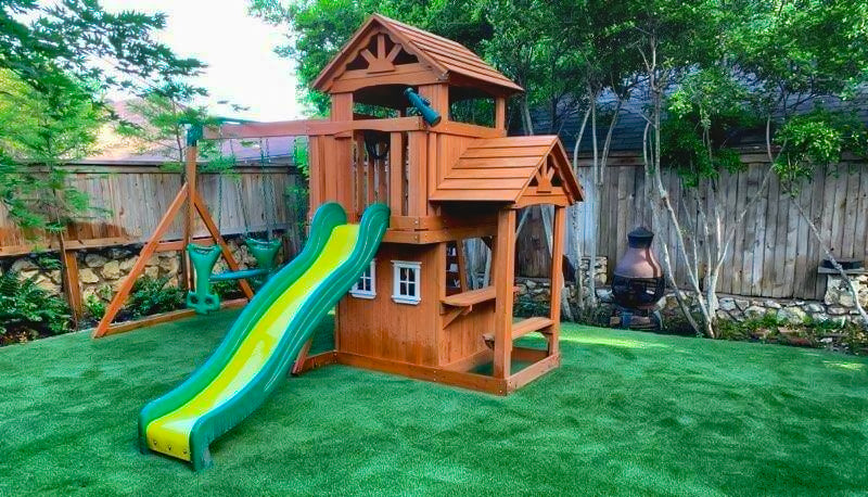 wooden playset with one slide on artificial turf