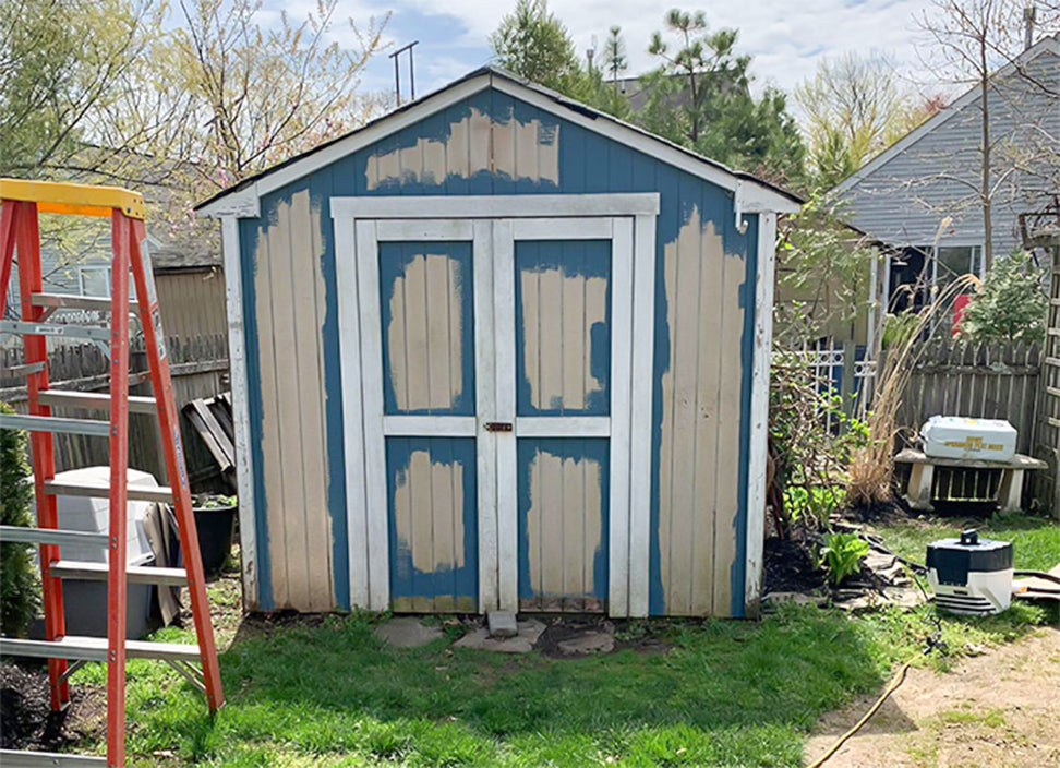 wooden shed with double doors in the process of painting