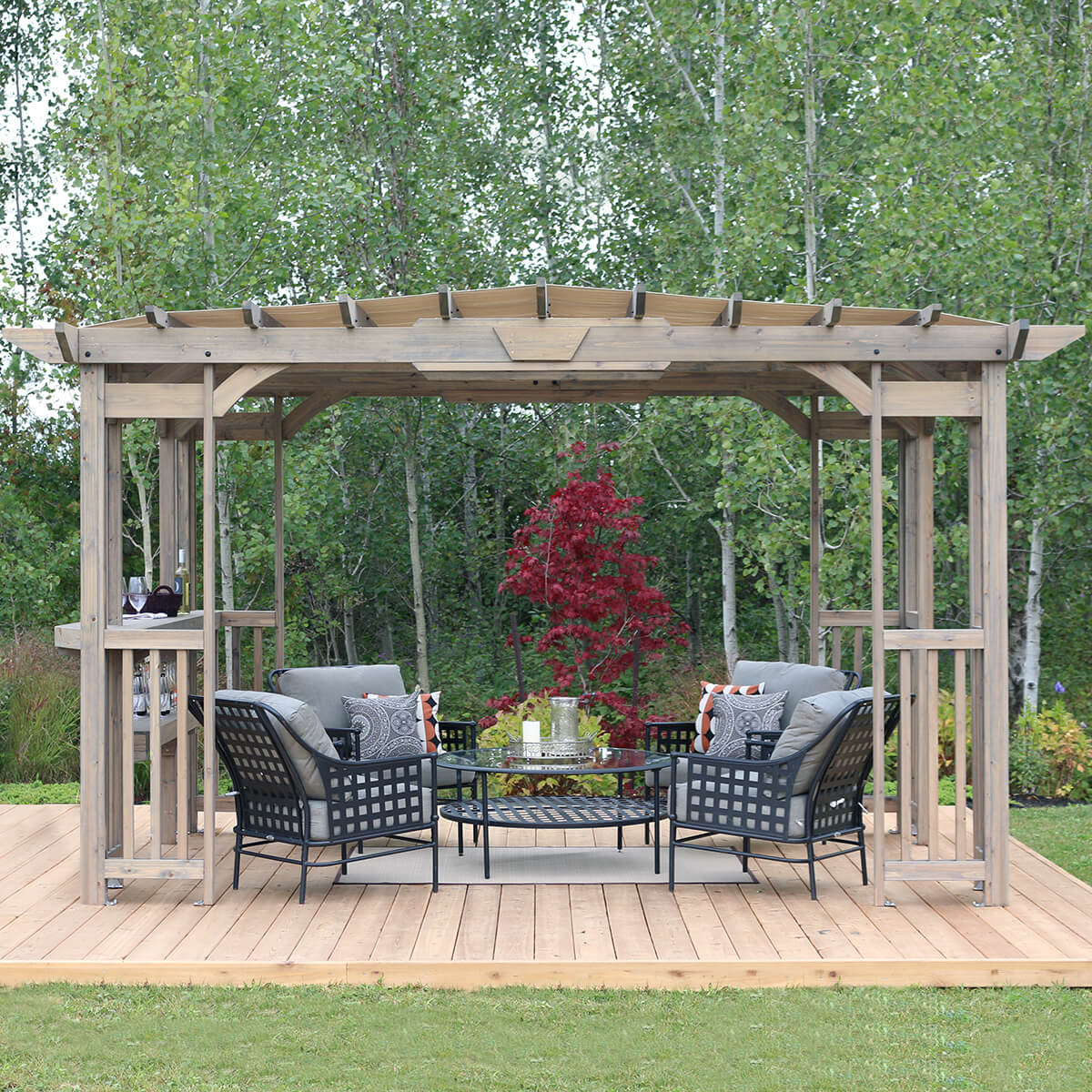 Yardistry Madison 10 x 14 Cedar Pergola in Timber Gray set against a lush, natural forest backdrop, enhancing the beauty and utility of an outdoor seating area.