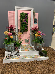 Photo of a pink door decorated with vases filled with flowers of all different colors