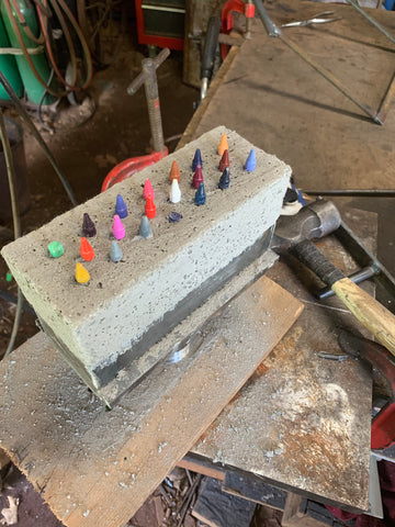 An image of the process for making a ribbon burner. Crayons are used to create holes for the burner when pouring the high temperature castable for the burner.