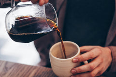 Coffee being poured into a ceramic mug.