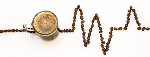 Coffee cup in a line of coffee beans that form the line of a heart beat monitor.