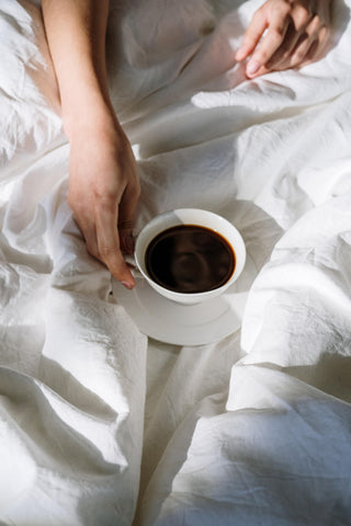 Cup of coffee on a bed in the morning.