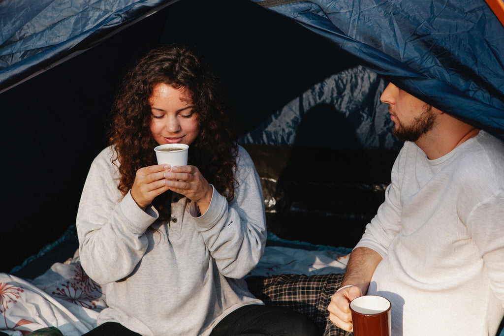Young couple drinking morning coffee while camping.