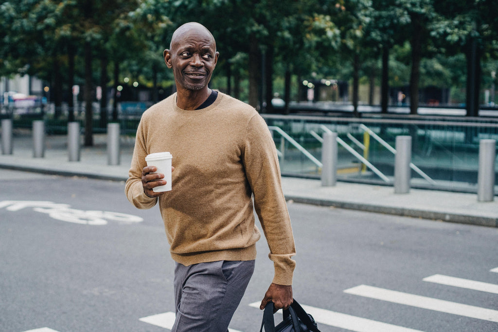 Man crossing the road with a disposable coffee cup.