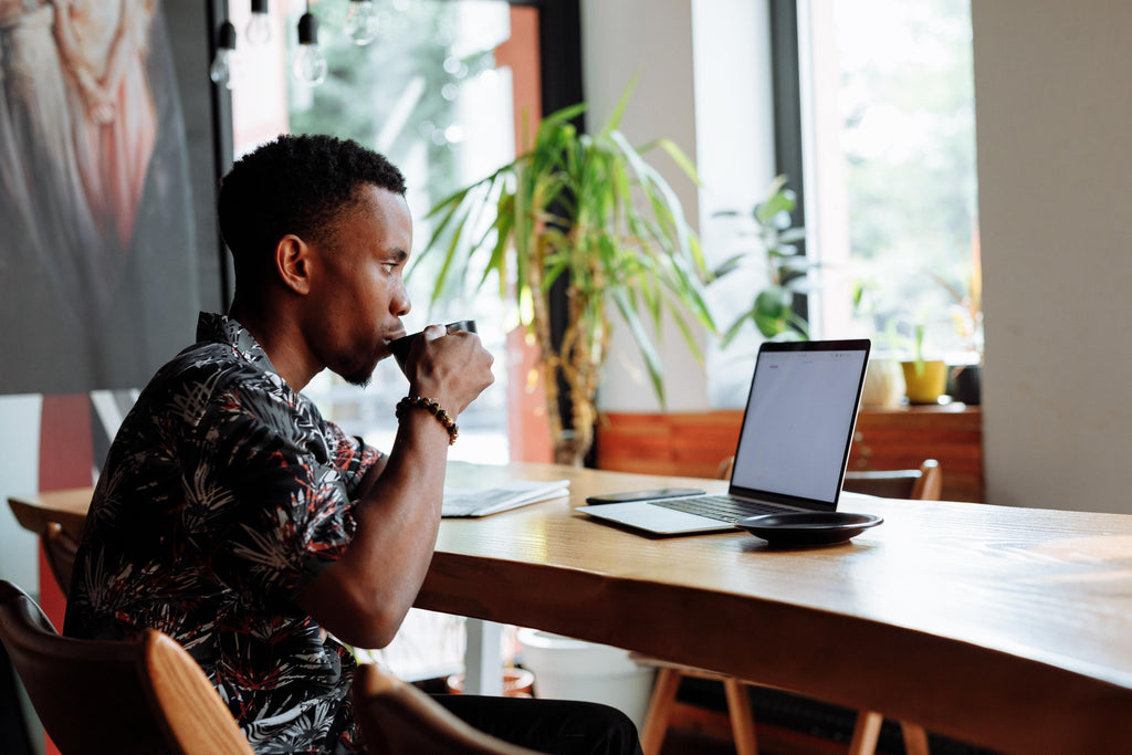 Man drinking coffee while working at a cafe.