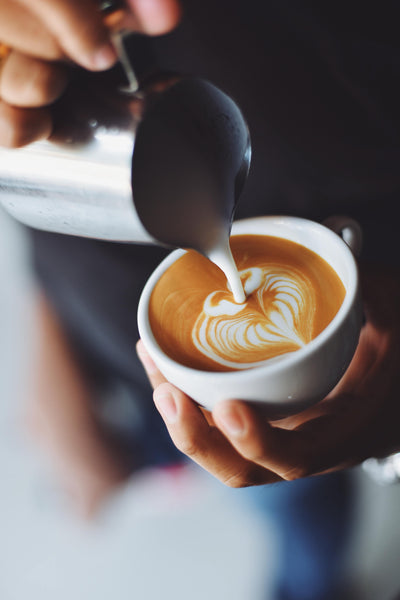 Hands pouring milk for latte art.