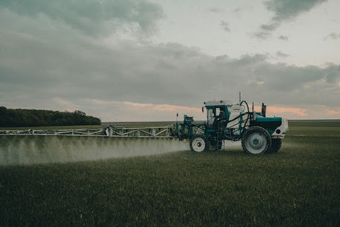 A tractor sprays a field with pesticides. 