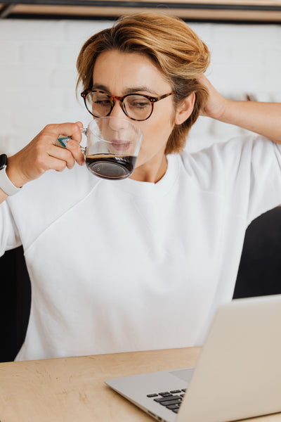 Woman drinking coffee in front of her computer.